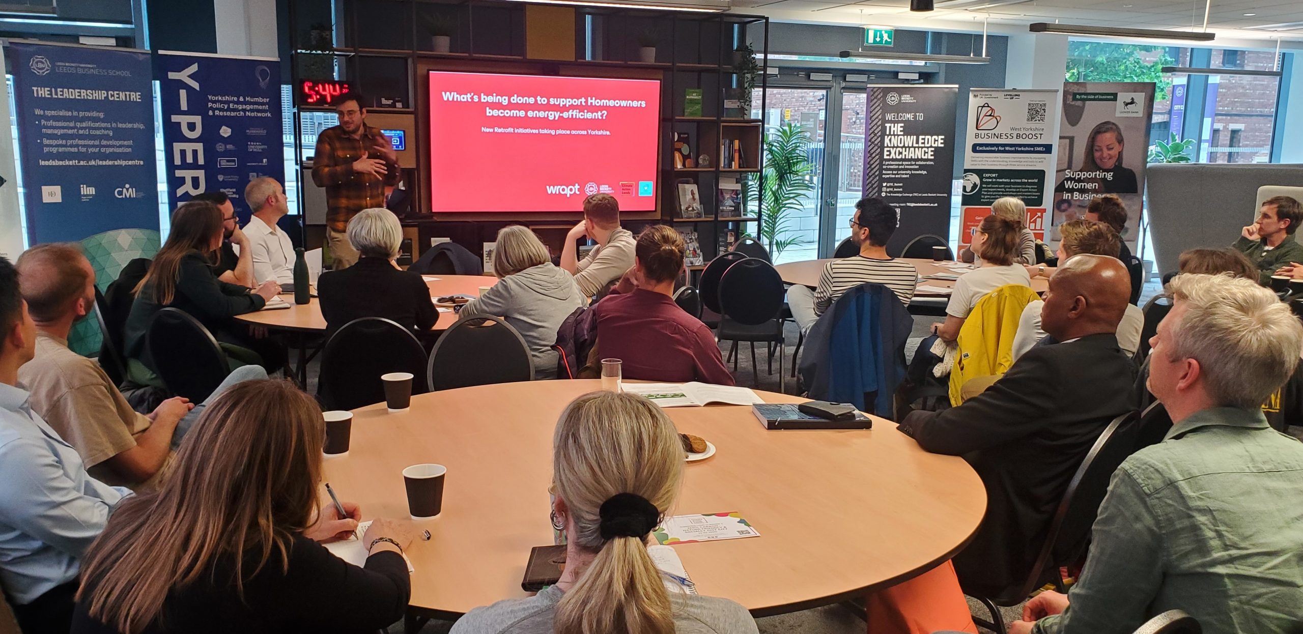 Group of people watching a speaker give a presentation
