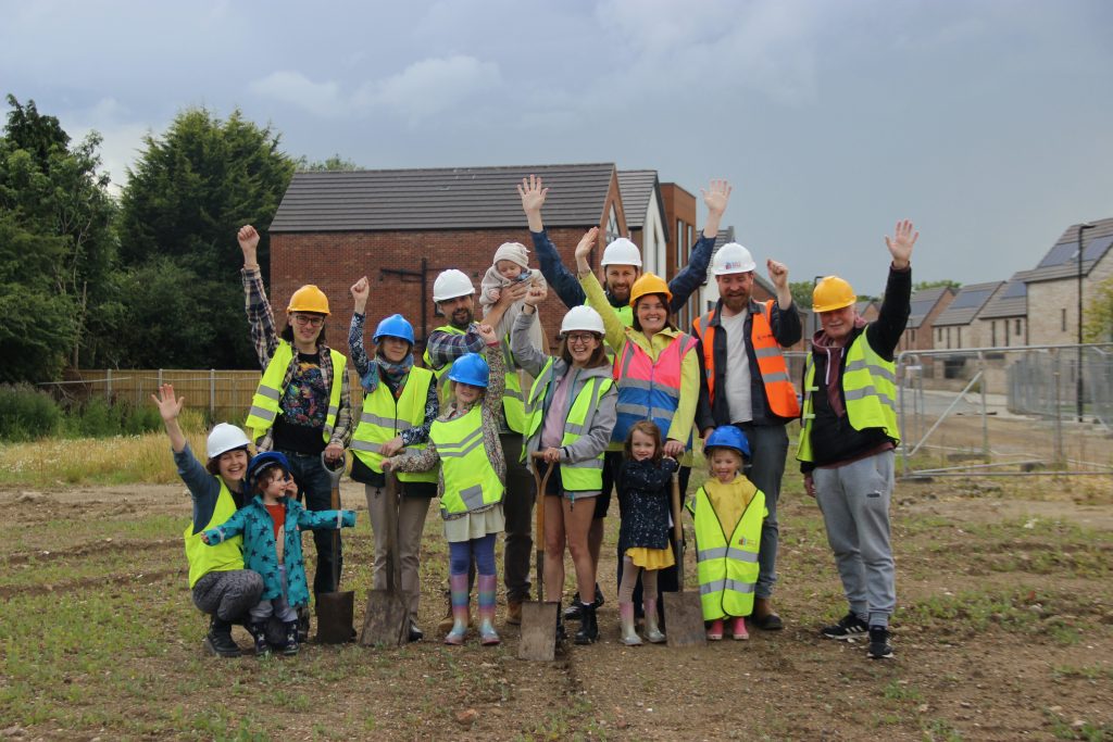 group of people standing on a site waving in hard hats