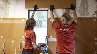2 people putting up insulation